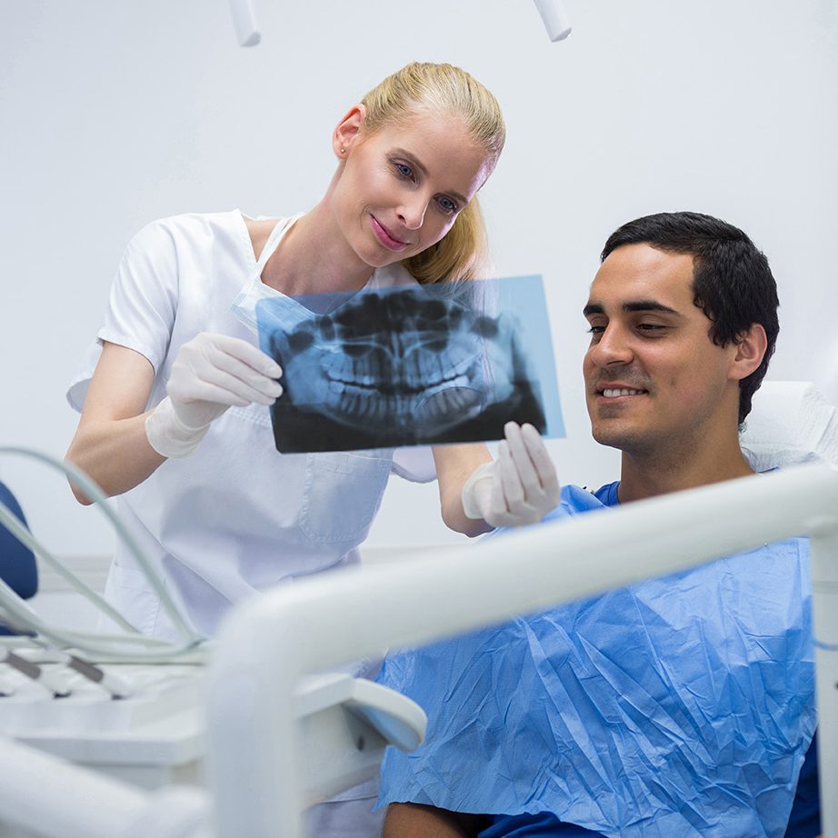 Dentist showing dental x-ray to patient at clinic